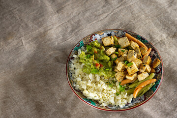 Vibrant cauliflower 'rice' bowl with marinated tofu, colorful pasta, and creamy avocado guacamole. A colorful, healthy feast!