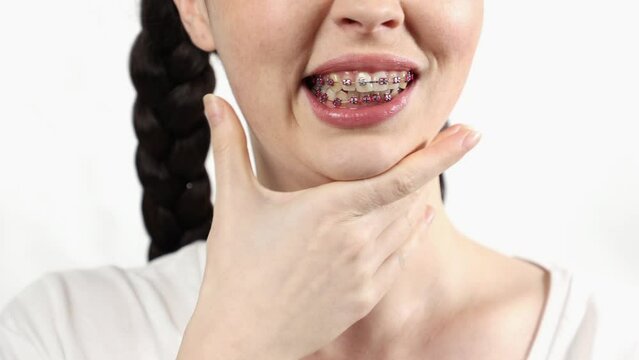 Close up of young woman with ligature braces on teeth suffering from pain. White background. Concept of orthodontic treatment