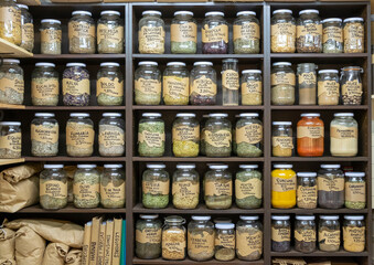 Glass jars containing medical herbs, dried medicinal plants to cure or improve diseases for sale in a herbalist. Alternative medicine.