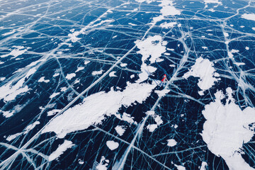 Happy woman tourist on ice skates and with long red scarf on frozen lake Baikal. Concept winter tourism freedom. Aerial top view