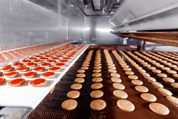 Modern line for bakery cookies with red jam and chocolate. Food industry, biscuit production in factory on conveyor belt