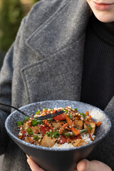 Woman eating tasty rice, meat and vegetables with fork, closeup