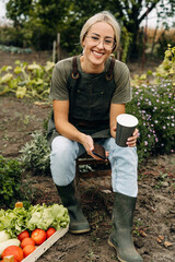 Smiling woman sitting on a stool in the garden.