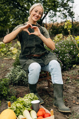 Joyful woman loves gardening. Shoving hearth shape with hands in the garden.