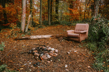 Old brown fabric sofa abandoned in a forest. Fly tipping, ripped and torn material, no people