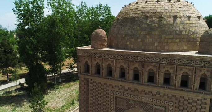 A drone flies close around a Ismoil Somoniy madrasah on a sunny day. Uzbekistan, Bukhara.