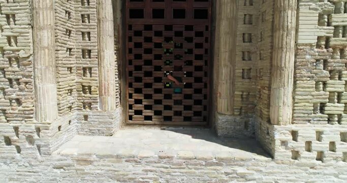 A drone flies close around a Ismoil Somoniy madrasah on a sunny day. Uzbekistan, Bukhara.
