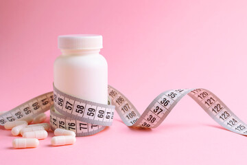 centimeter tape and pills on a colored background with space for text. concept of losing weight,...