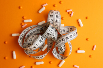 centimeter tape and pills on a colored background with space for text. concept of losing weight,...