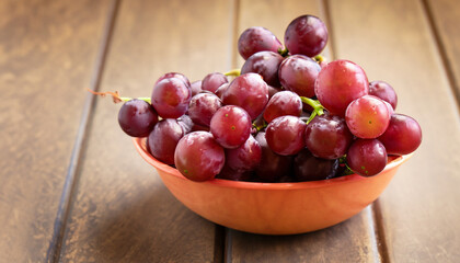 Red grape in a bowl on wooden, Healthy fruit concept (selective focus; close up)