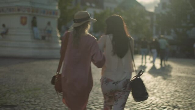 two female people friends having a summer sunset stroll in the city center