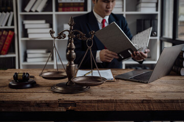 Asian male lawyer working in office with laptop and scales, judge hammer, legal consultant concept.
