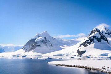 Antarctic landscape with icebergs in the ocean and blue sky