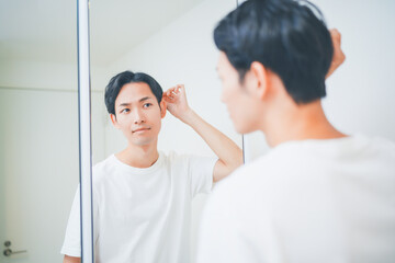 Obraz premium 洗面所でヘアセットをする男性