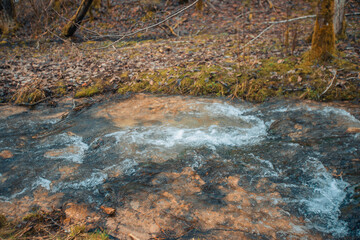 A peaceful autumn forest reflected in a peaceful flowing river. A serene waterfall in a lush autumn forest surrounded by rocks.