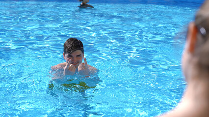 Young happy man flirting and beckoning his girlfriend in the swimming pool. Clip. Concept of travelling and vacation.