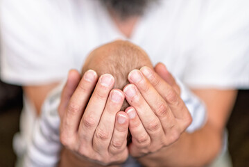 Dad holding his newborn baby in his hands, man's hands holding baby's head, top of head view - 683341817