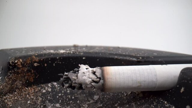 Burning cigarette in dirty ashtray close up 4K