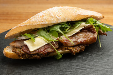 closeup of pork sandwich with cheese and green shoots