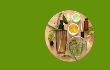 Flat lay of cleansing anti-aging natural herbal cosmetics with aloe extract on wooden and green background. Advertising of new cosmetic products. Moisturizing skin care. Top view, copy space, mockup