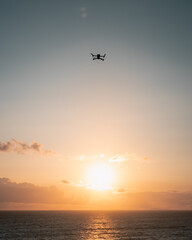 A drone fluing against the sunset sky