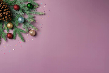 Colorful balls on Christmas tree branches on a purple background and space for text. Top view