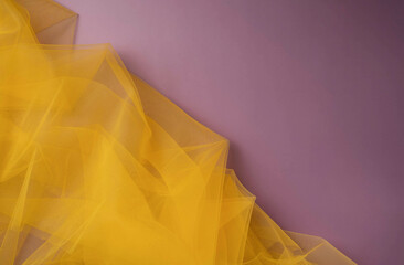 Yellow tulle fabric texture top view. Violet background.