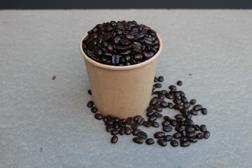 Coffee beans in a brown paper cup and white background