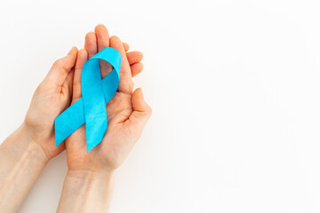 Blue ribbon symbol of colon or prostate cancer with hands. Medical support and prevention