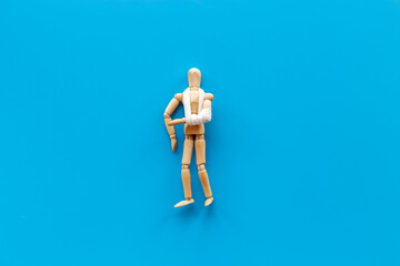 Wooden dummy man with broken arm - arm in bandage. Medical insurance and healthcare concept
