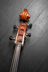Beautiful classic brown double bass neck, double bass scroll and tuning pegs on a black wooden...