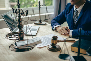 Asian male lawyer working in law office with hammer and scale and laptop, contract concept legal...