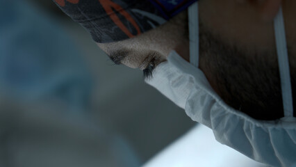 Close up of young surgeon in blue medical mask. Action. Face of a specialist in medical uniform...
