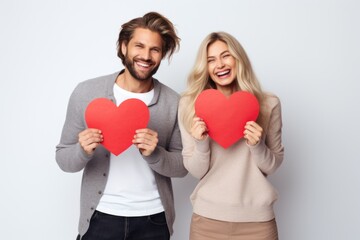 Fototapeta na wymiar Happy couple of man of woman laughing and holding red hearts on white backdrop. Generated AI
