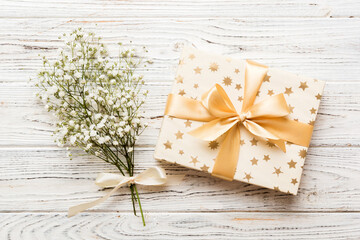 Gift or present box and flower gypsophila on light table top view. Greeting card. Flat lay style with copy space
