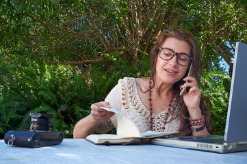 Digital nomad communicating through his smartphonel in the wild while working outdoors. With...