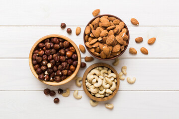 Assortment of nuts in wooden bowl on colored table. Cashew, hazelnuts, walnuts, almonds. Mix of nuts Top view with copy space