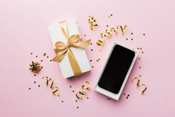 Opened gift box with gold ribbon and smartphone on color background, top view. Blank open box...