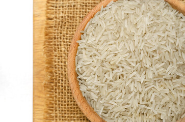 Uncooked basmati rice in a wooden bowl on a burlap on a cutting board. Concept of Water-Conserving Products. Saving water. Horizontal orientation. Top view.