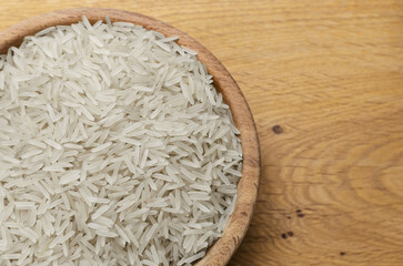 Uncooked basmati rice in a wooden bowl on a wooden table. Concept of Water-Conserving Products. Saving water. Horizontal orientation. Top view.