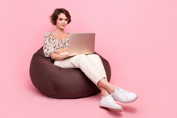 Full size photo of intelligent girl dressed print stylish blouse sit on pouf look at laptop write...