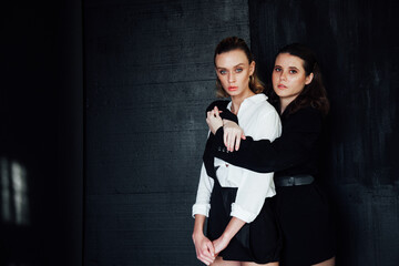 Two female friends in a room on a black background