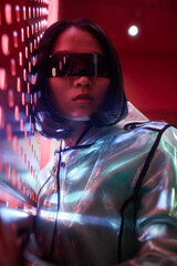 Vertical closeup portrait of young Asian woman wearing cyberpunk style outfit and looking at camera