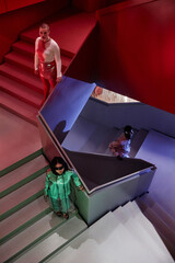 Futuristic fashion portrait of young people standing on abstract architectural staircase in neon...