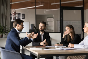 Project manager man speaking on business team brainstorming meeting, offering ideas to listening coworkers. Work colleagues discussing job tasks, project management with leader