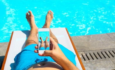 Young man lying on sunbed near pool with phone