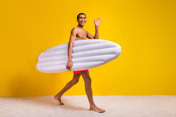 Full length photo of cool good mood shirtless man walking waving arm holding floating matrass...