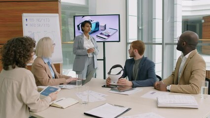 Young businesswoman standing in crowded conference room wearing grey formal suit answering questions from audience