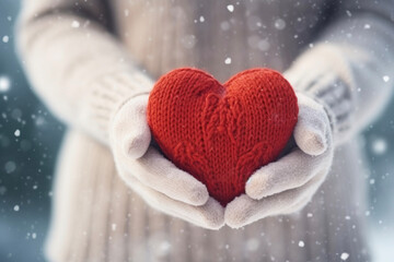 Knitted red heart in hands. Holiday gift. Winter comfort