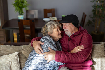 Senior couple wearing winter clothing inside home due to high electricity prices